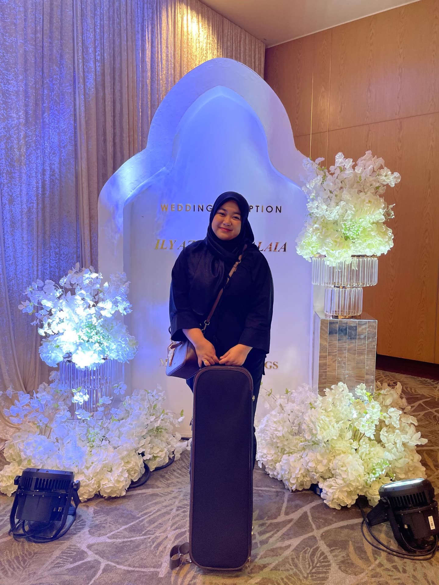 Farah Li with her violin case at a wedding reception backdrop